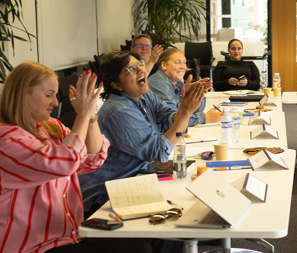 Workshop attendees applauding and laughing at the end of an advanced social media workshop.