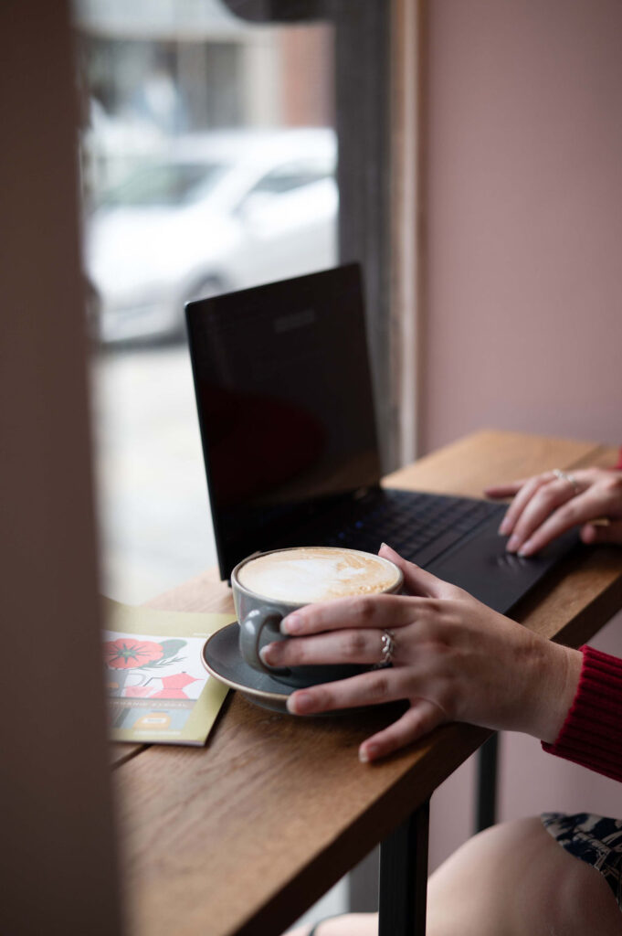 A latte and a laptop on a table in a cafe.