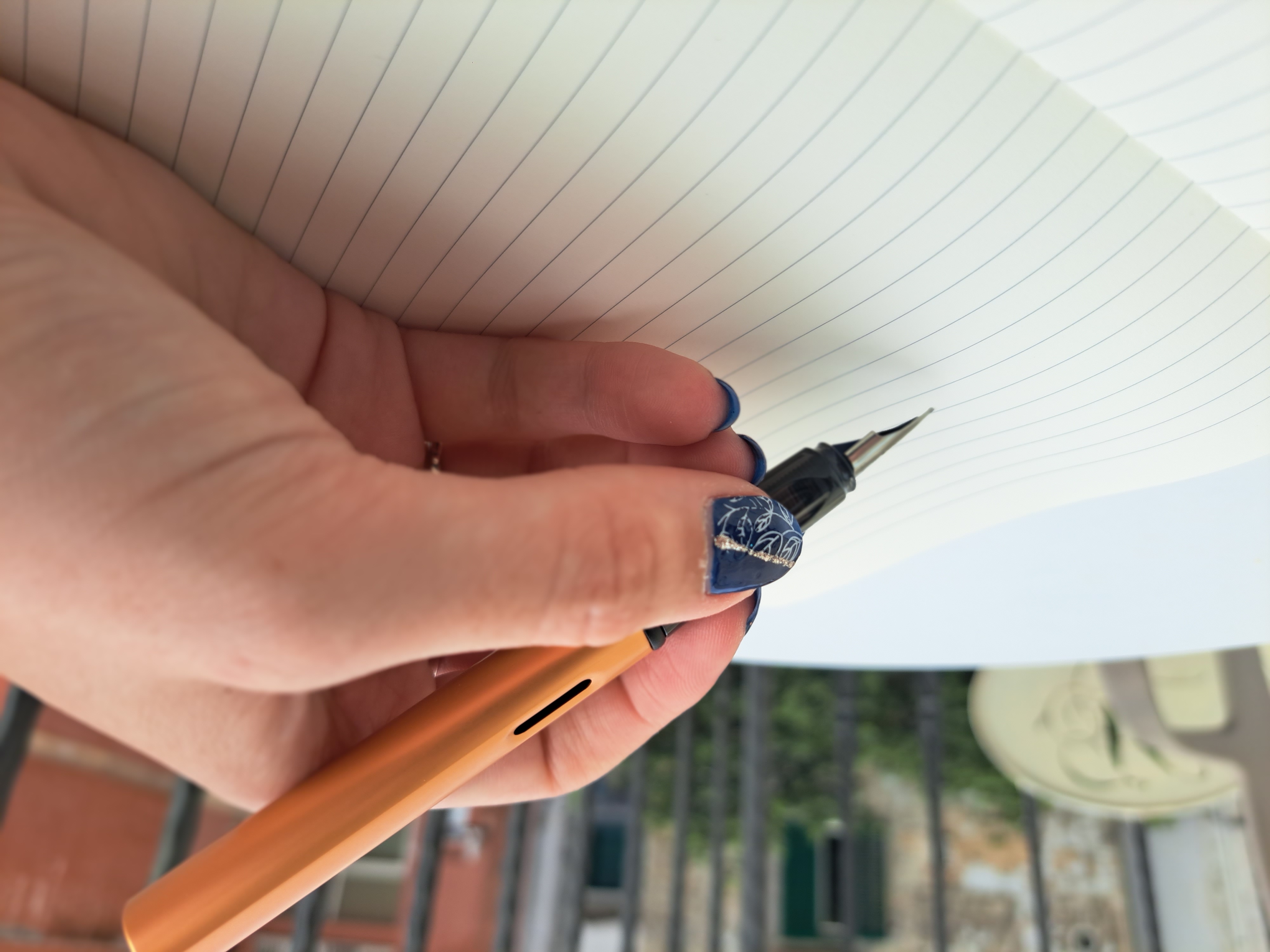 A hand holding a pen above an empty page.