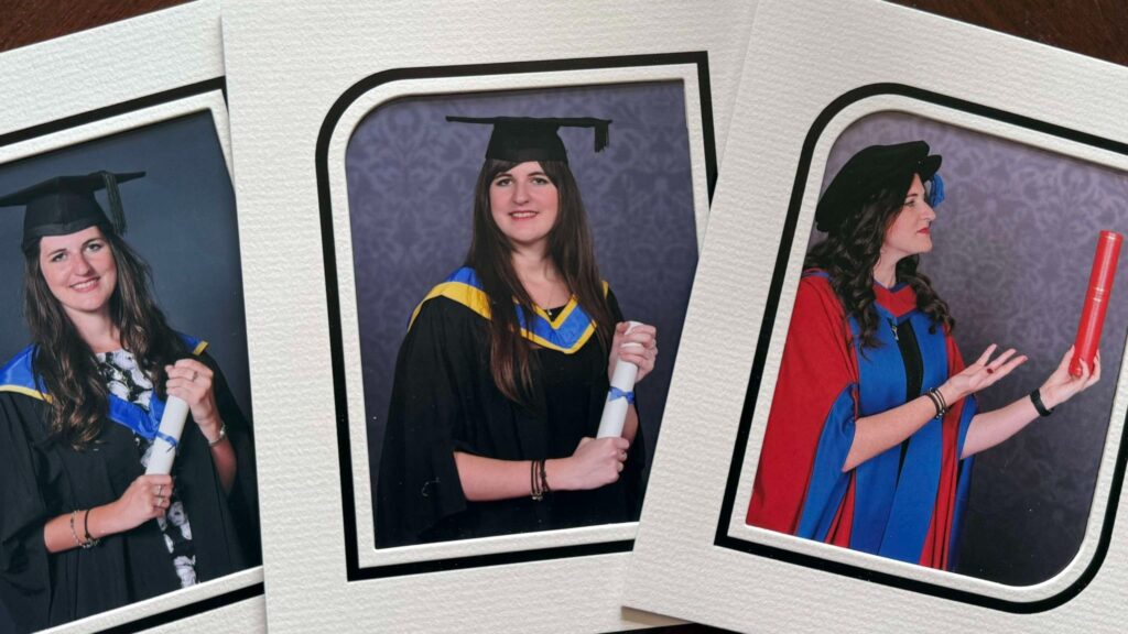 Three graduation photos arranged next to each other on a table. The images are of Eleanor Bryan getting a degree, then a Masters, then a PhD.