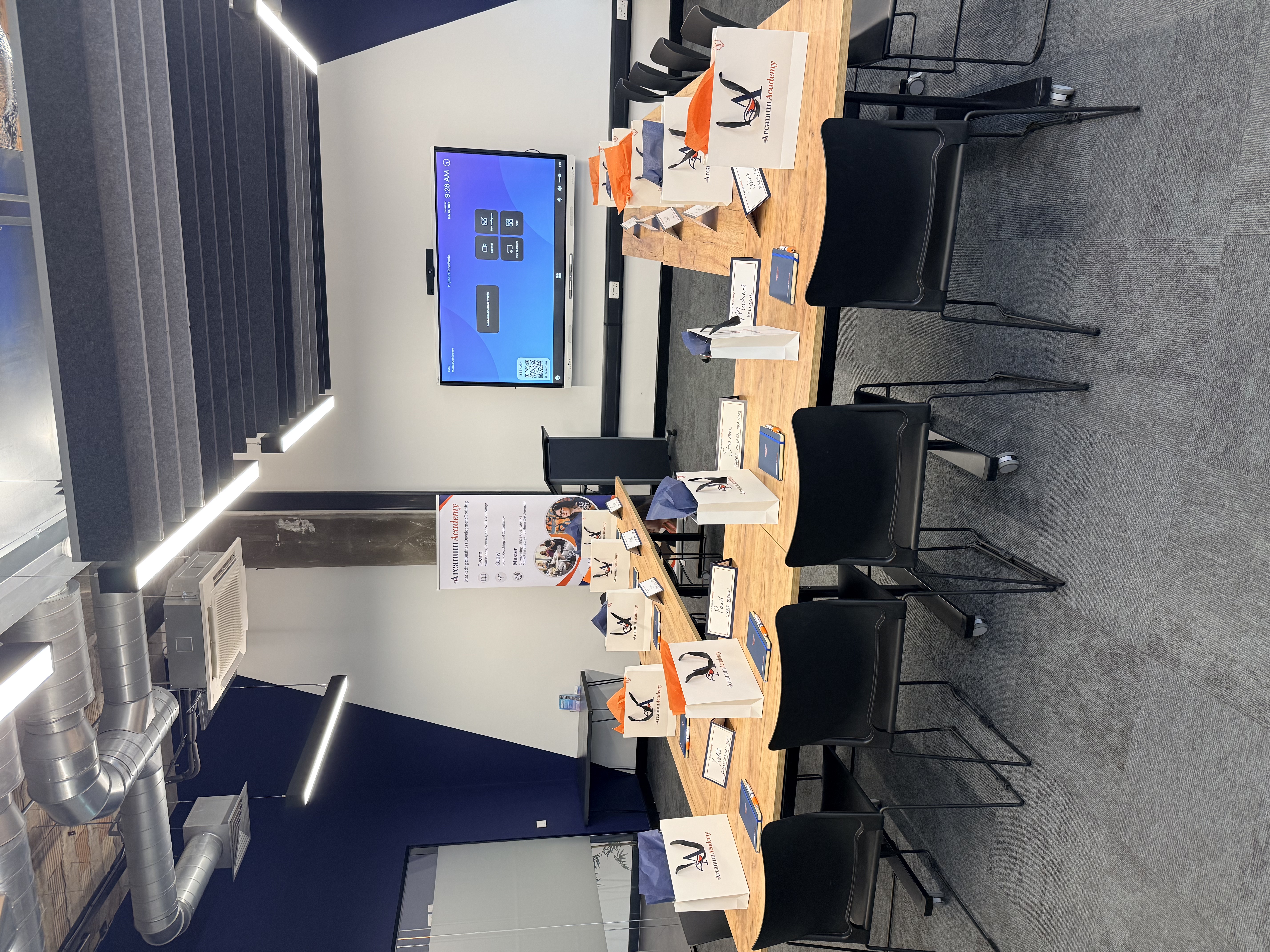 A conference room set up for an Arcanum Academy social media workshop, with gift bags and notebooks on the desks.