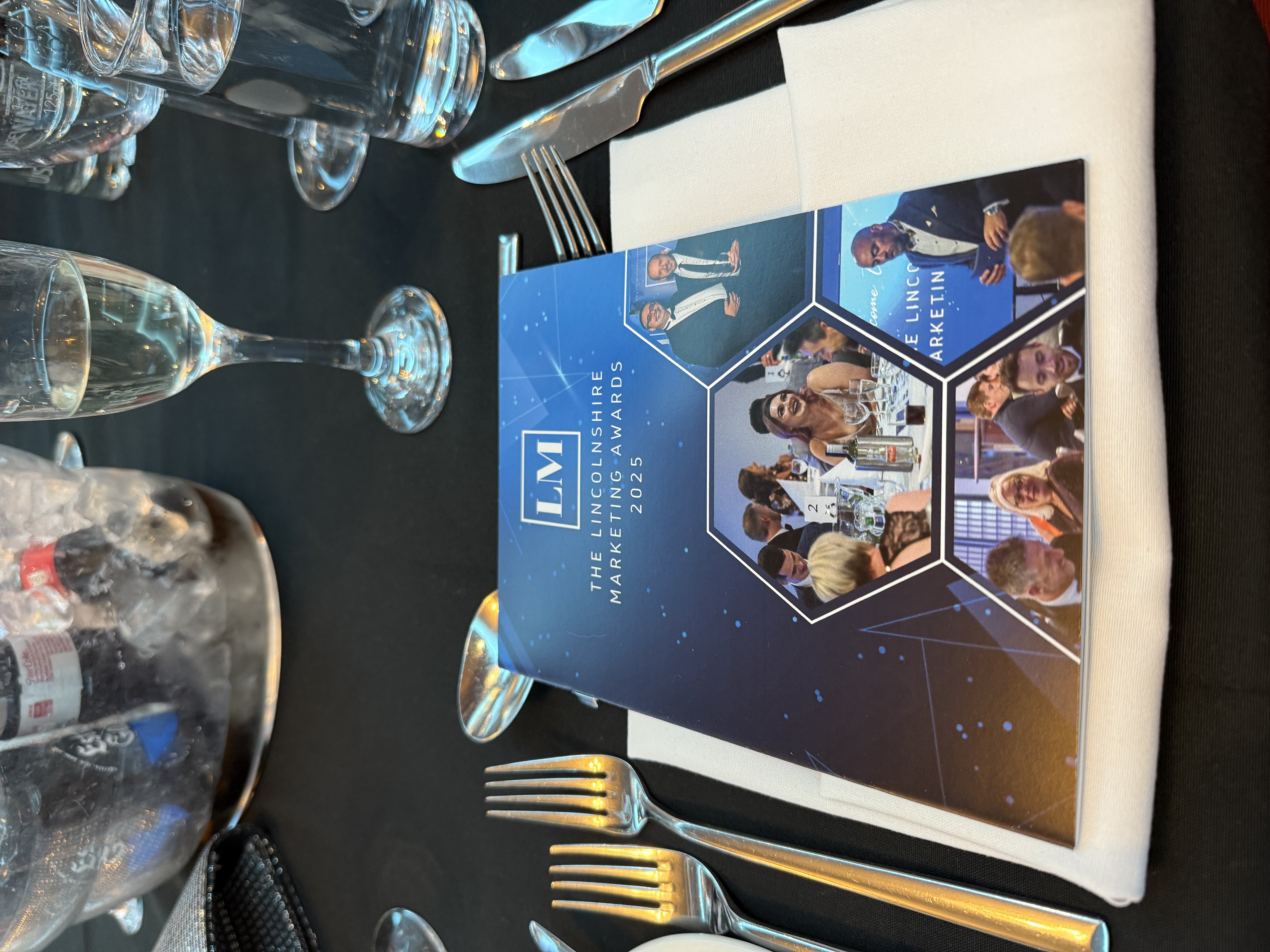 A brochure for the Lincolnshire Marketing Awards on a table at an award ceremony.