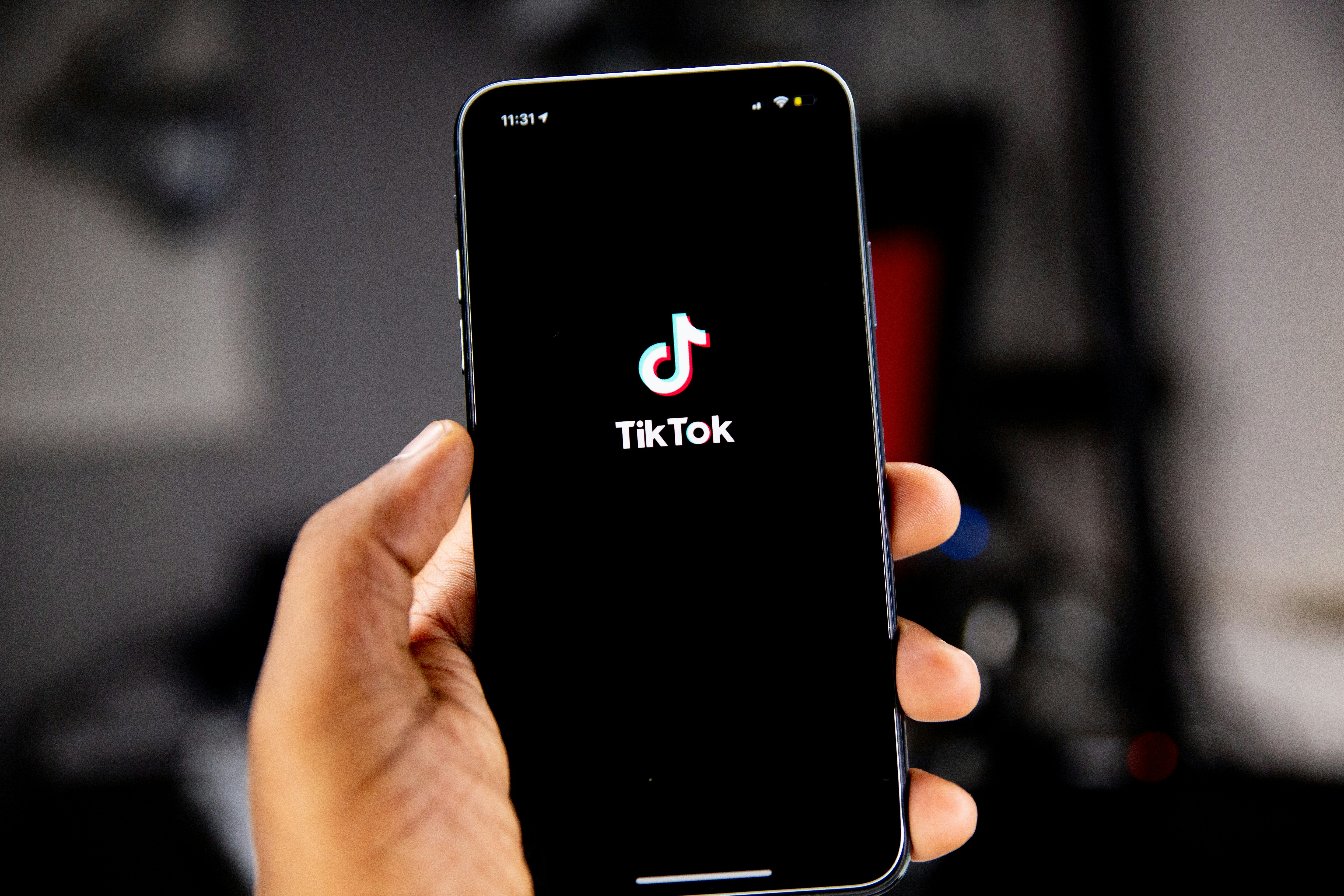 A hand holding a phone with the TikTok logo on the screen.