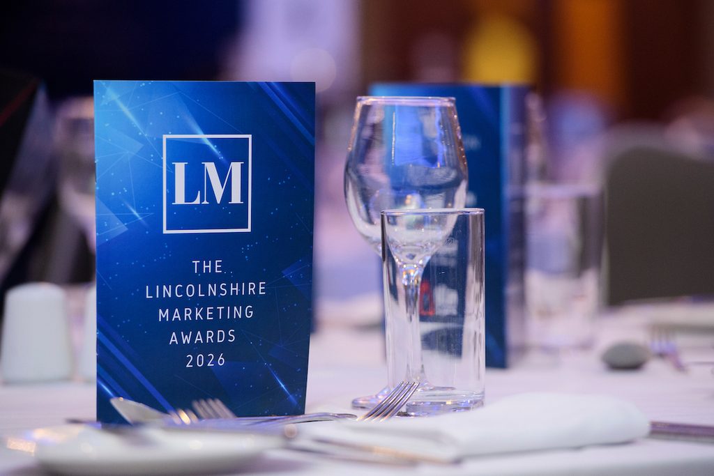 A programme for the Lincolnshire Marketing Awards and a wine glass on a table.